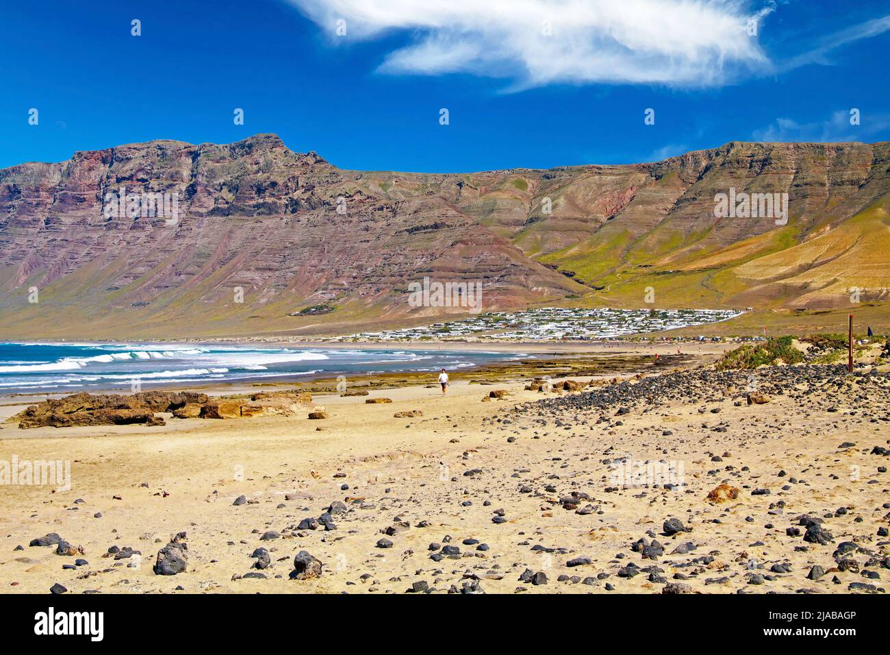 Beautiful wild rough lagoon, secluded white village located at the bottom of a rock face, sand beach, ocean waves  - Playa de Sotavento Jandia, Risco Stock Photo