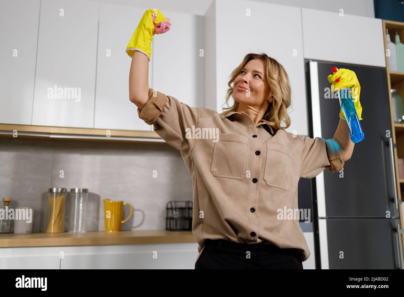 Cleaning lady in rubber gloves with cleaning agent and rag in her hands