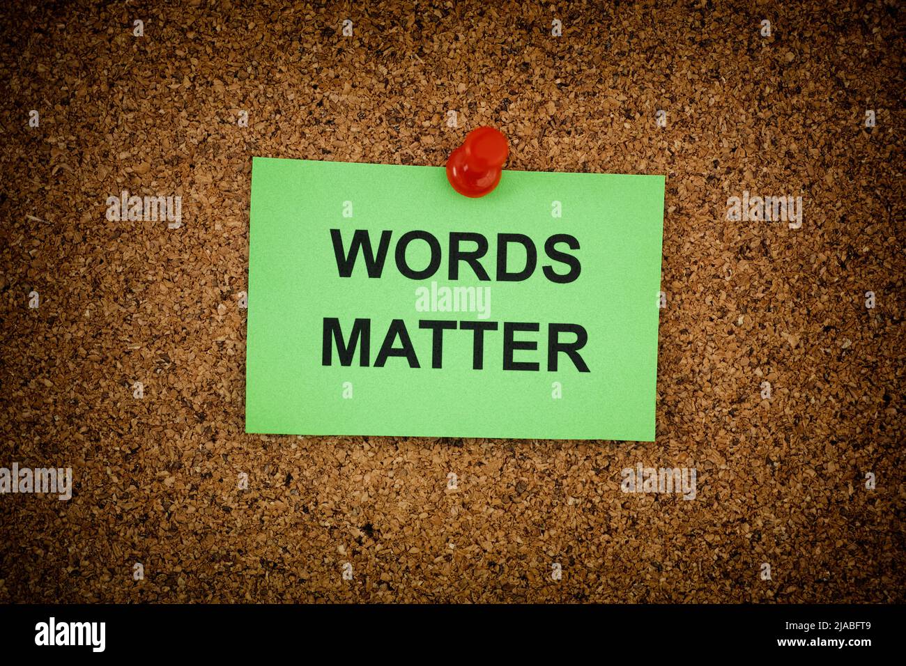 A sticky note with the phrase Words Matter on it pinned to a cork board. Close up. Stock Photo