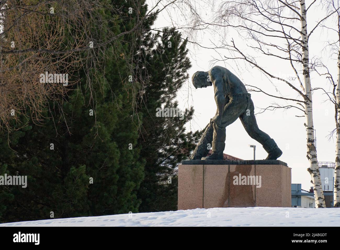 Rovaniemi, Finland - March 20th, 2022: A Bronze statue of a lumberjack debarking a log, on a snowy day in Rovaniemi, Finland. Stock Photo