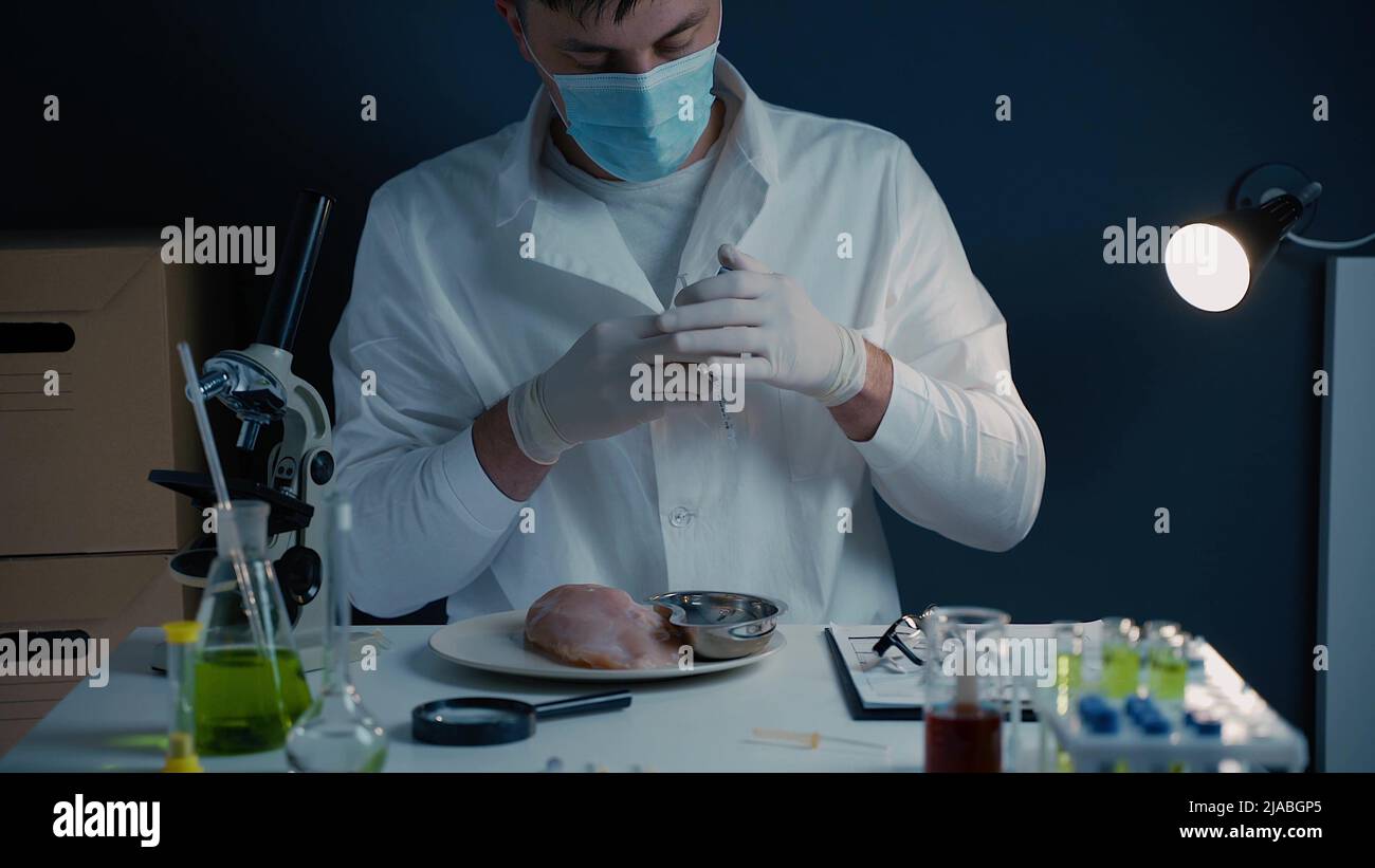 Genetically modified meat. GMO food concept. Genetic injection. Food scientist injecting raw meat. Lab assistant testing GMO chicken. Food quality con Stock Photo