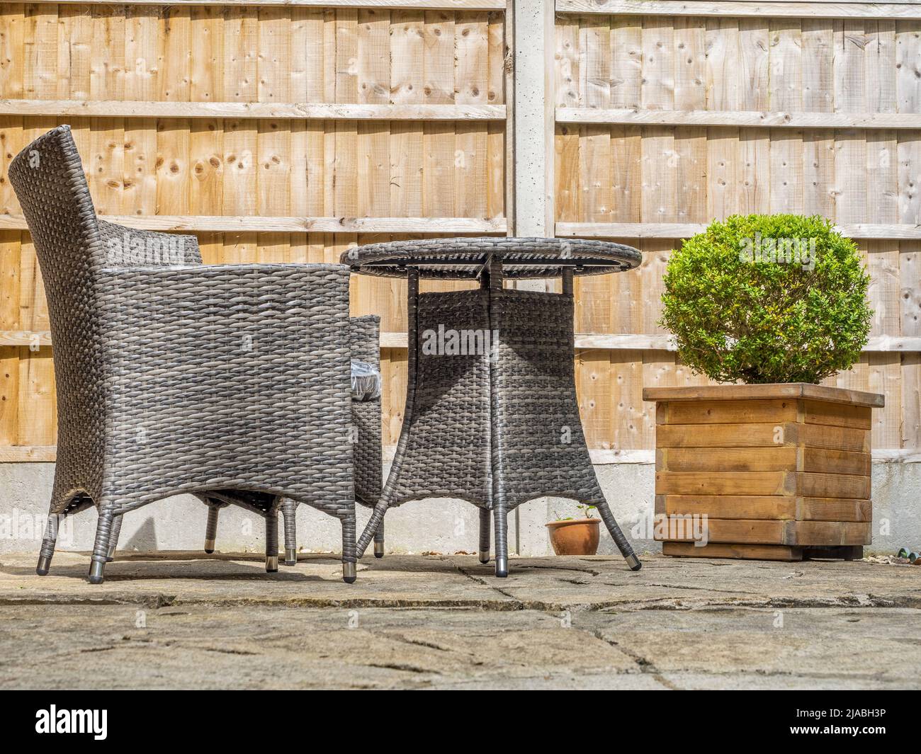 Grey Rattan garden chairs and table laid out on a patio Stock Photo