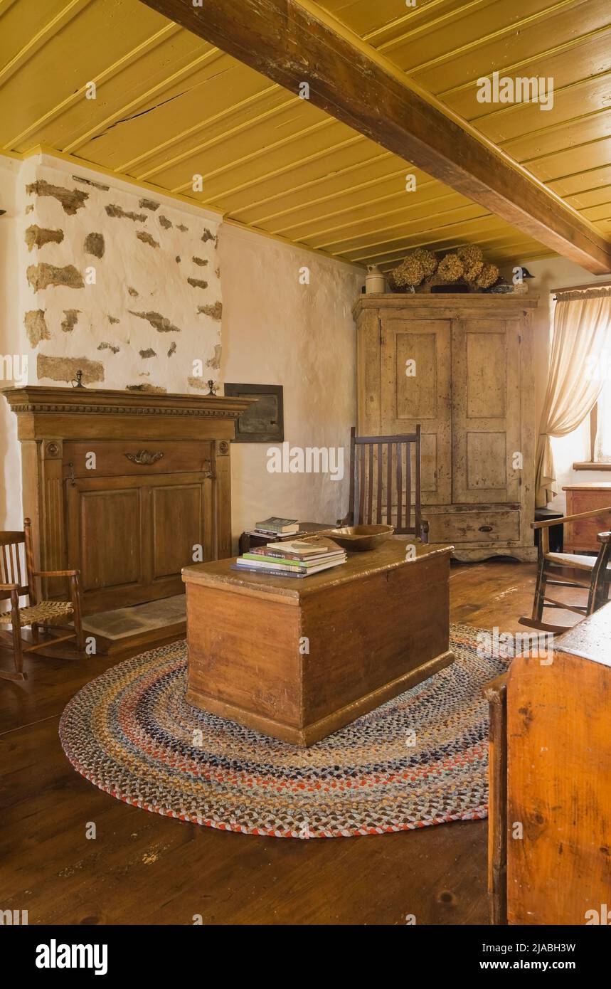 Antique chests, rocking chairs, armoire and furnishings in living room inside old circa 1840 Canadiana cottage style fieldstone home. Stock Photo