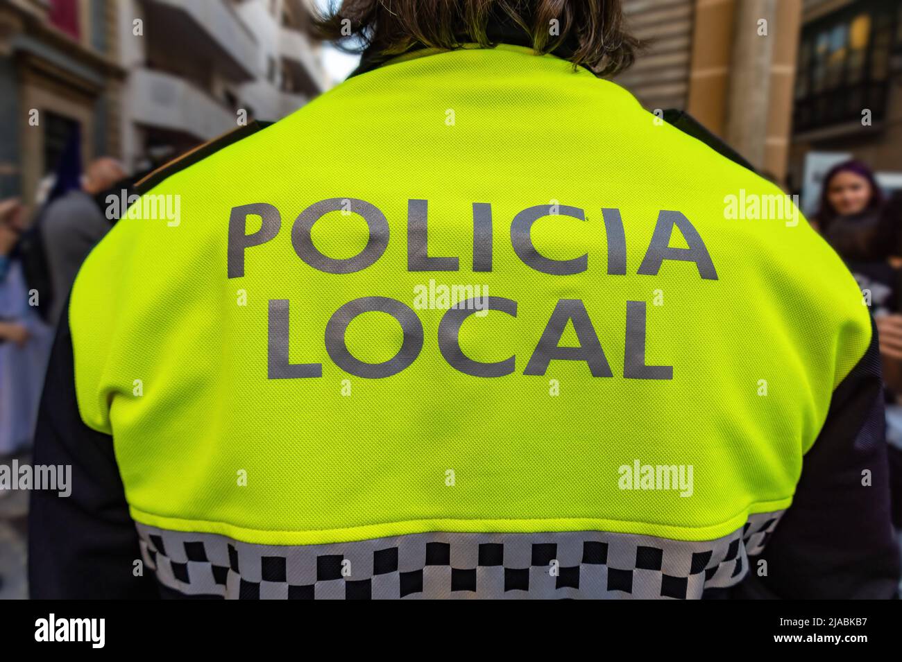 Back view of a police with the text in spanish 'Policia Local' that means local police maintaining the order in the streets Stock Photo