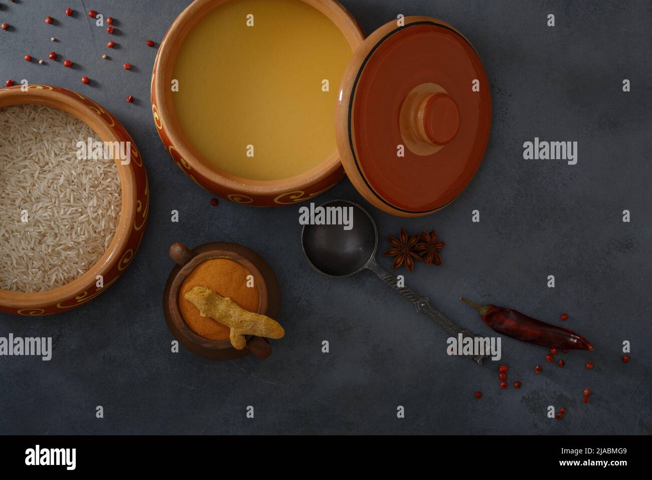 Homemade ghee, rice in a ceramic pot, red peppers and turmeric spices