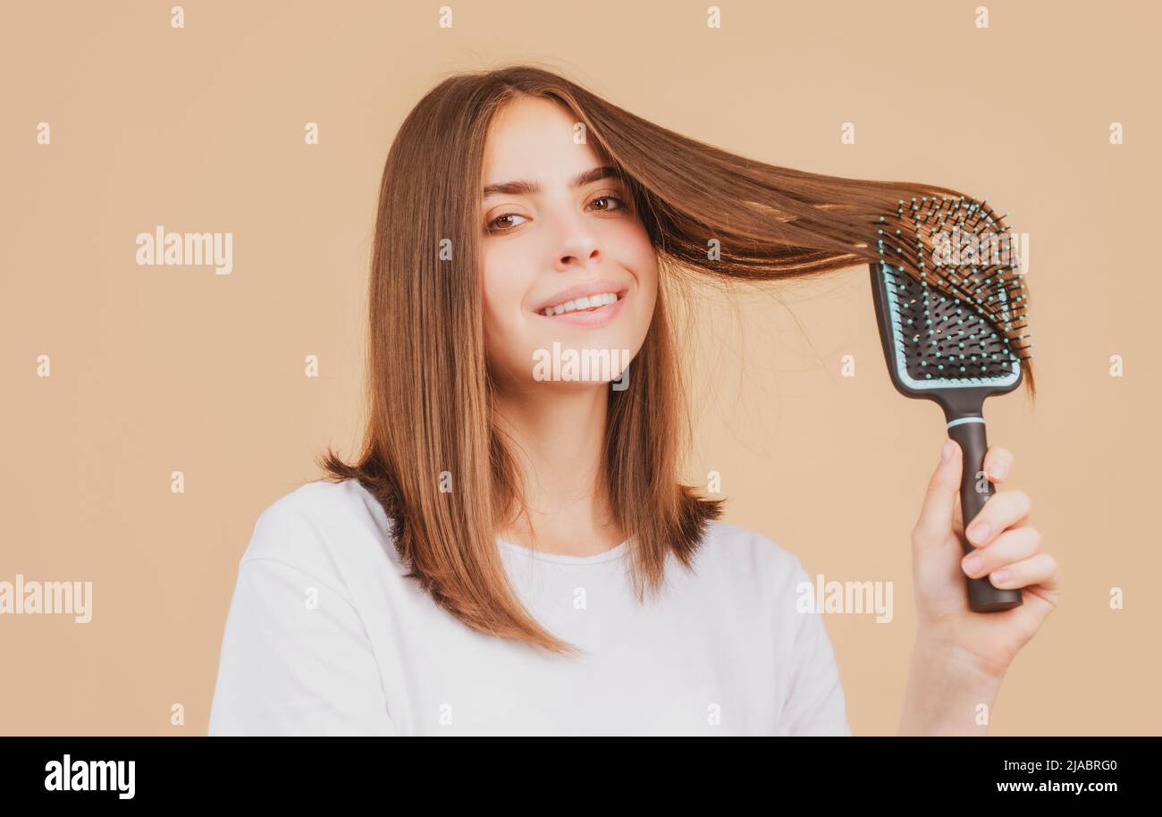 Beautiful woman combs her healthy hair. Combing healthy long straight