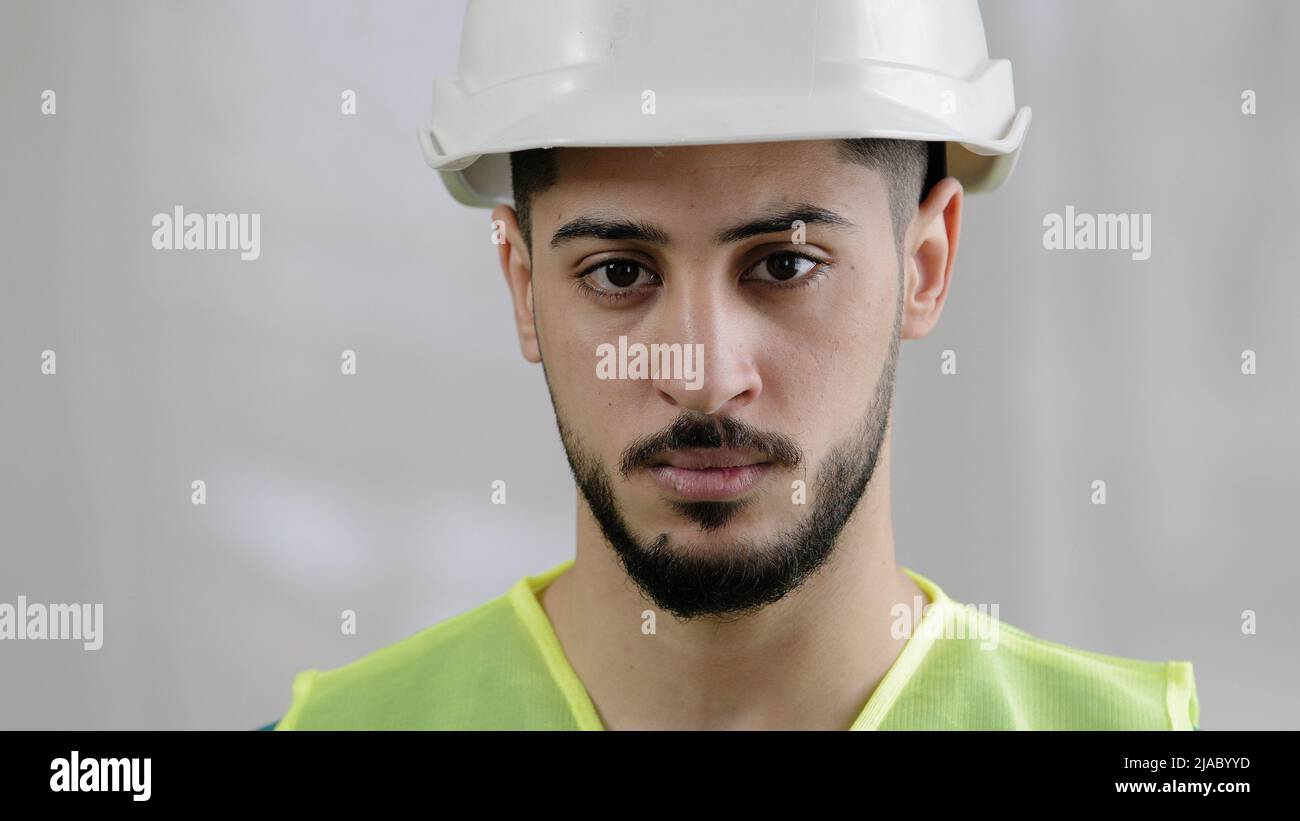 Close-up portrait of serious arabian man male foreman professional inspector builder mechanic engineer wear uniform safety helmet posing at camera Stock Photo