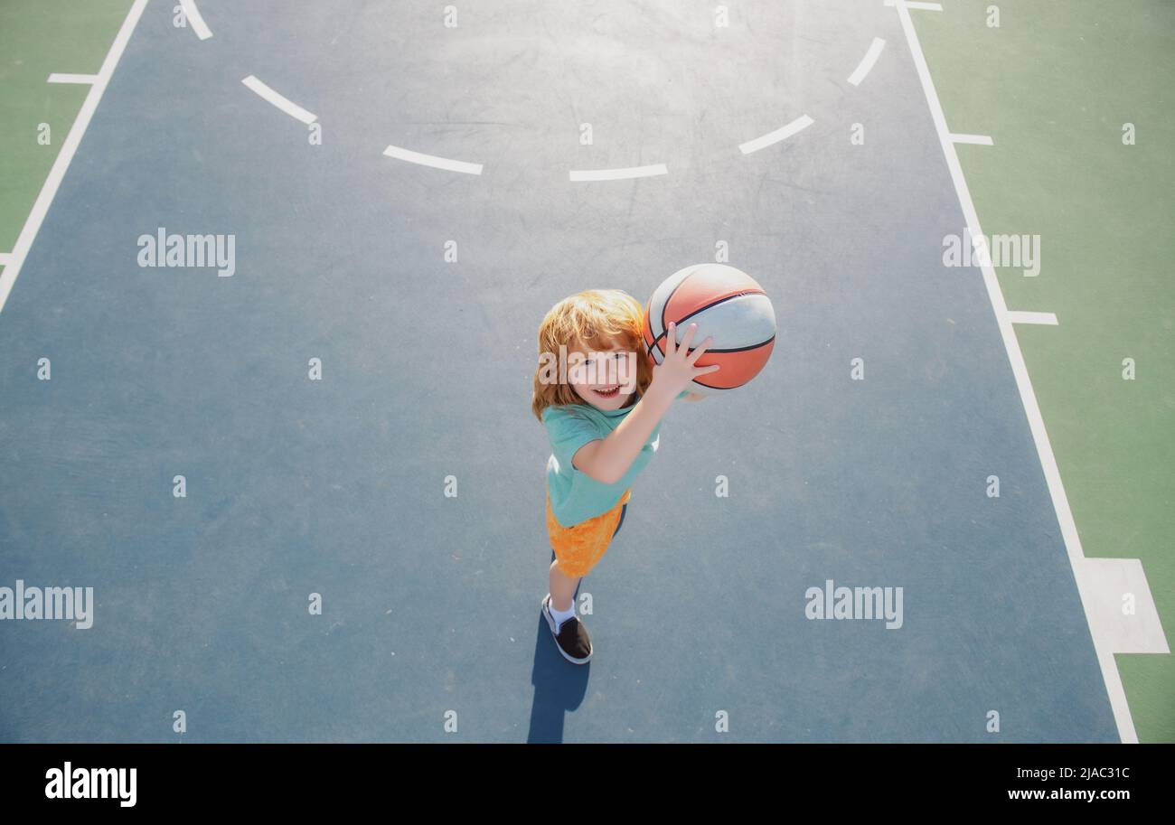 Child shooting Basketball ball and playing basketball, lower view wide