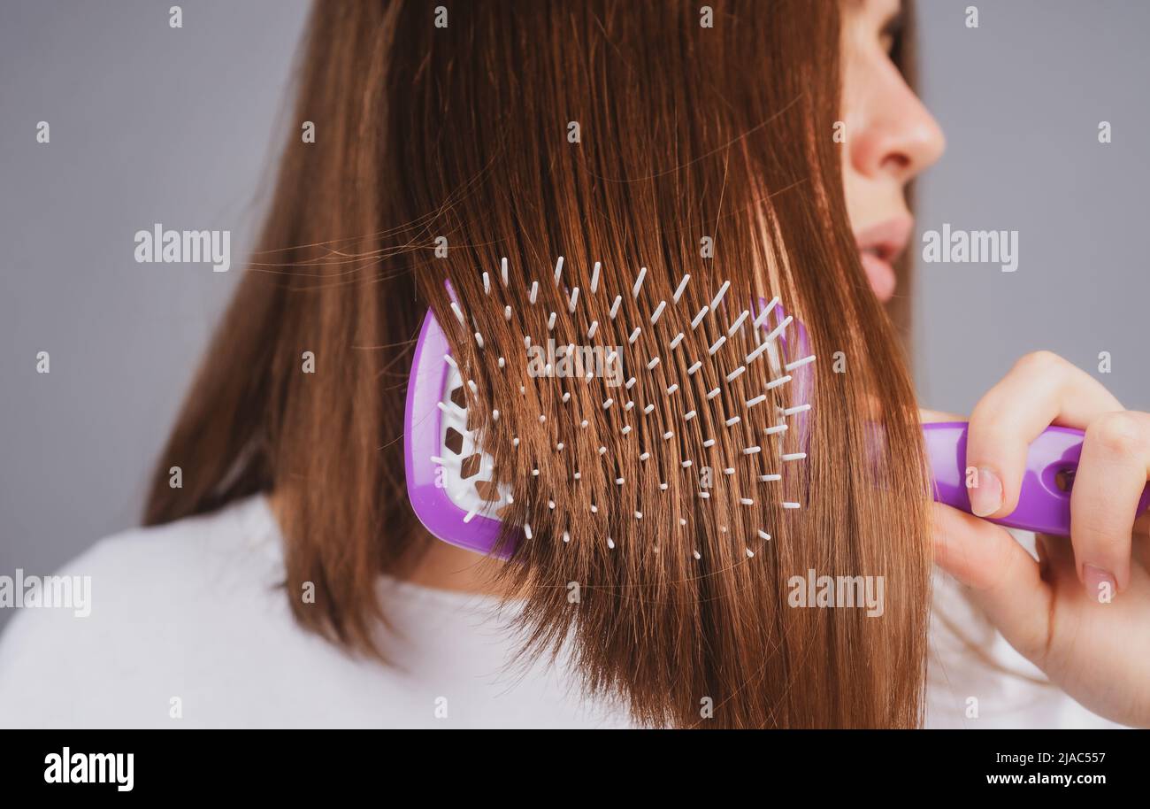 Close up woman brushing hair with comb. Beautiful girl with long hair