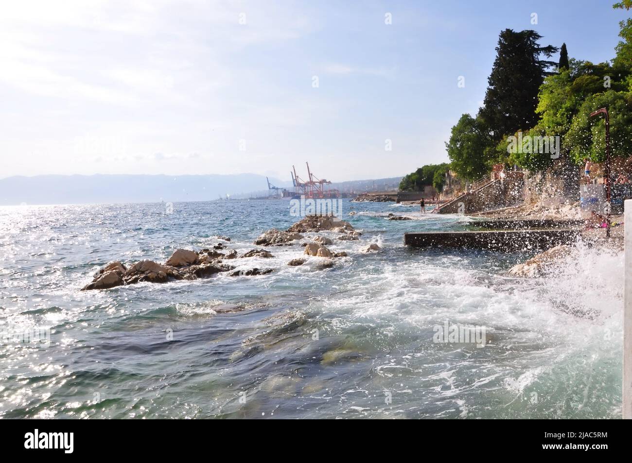 Wave splashing on a Croatian beach on early summer. Waves splashing into white rocks on the coast of Rijeka beach Pecine.Sea, big wave and splash over Stock Photo