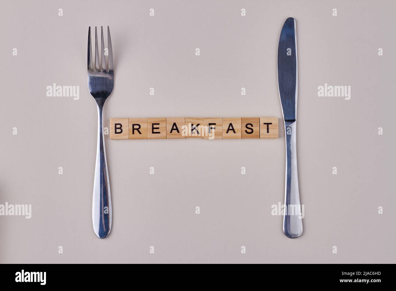 Cutlery and word breakfast made from vintage wooden cubes on white