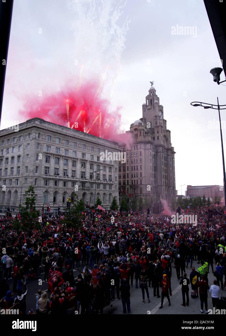 Pyrotechnics are set off as fans gather to watch the trophy parade in ...