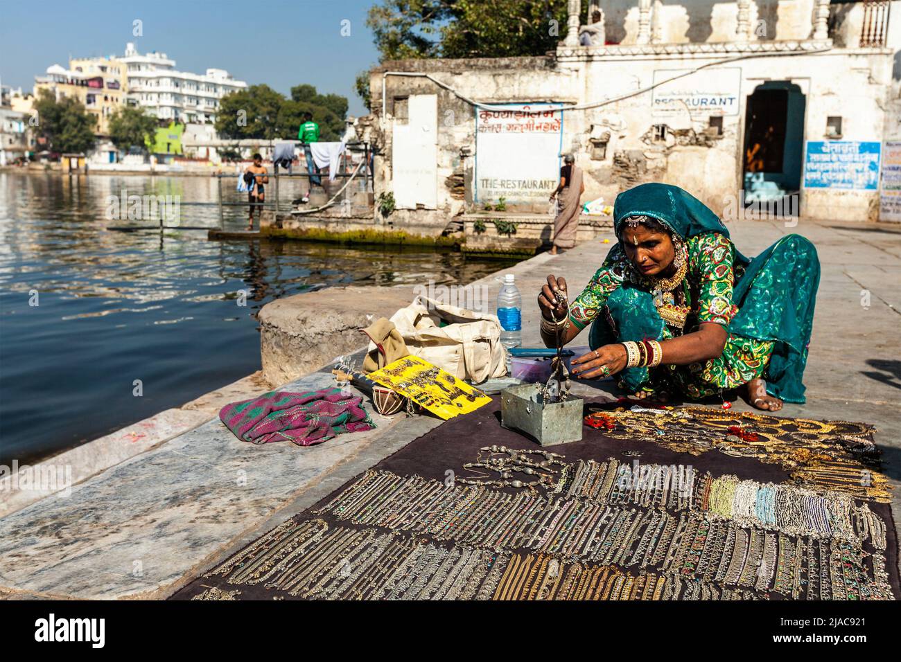 Woman in traditional clothing selling jewellery on ghat of Lake Pichola. Udaipur, Rajasthan, India Stock Photo