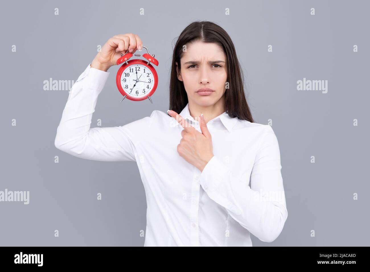 Surprised woman holding alarm watch. Isolated portrait. Stock Photo