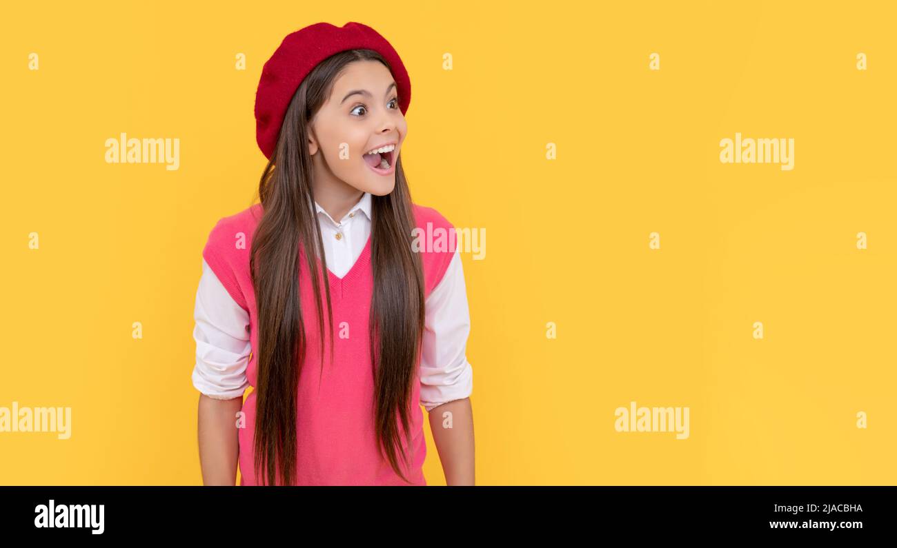 amazed teen school girl in french beret on yellow background, amazement