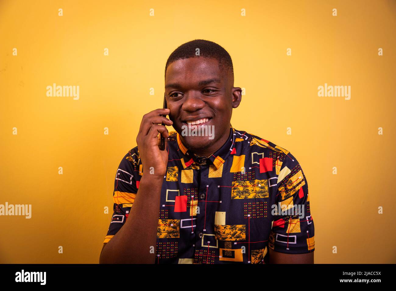 Young smiling black guy in photo studio on phone amused with girlfriend. Stock Photo