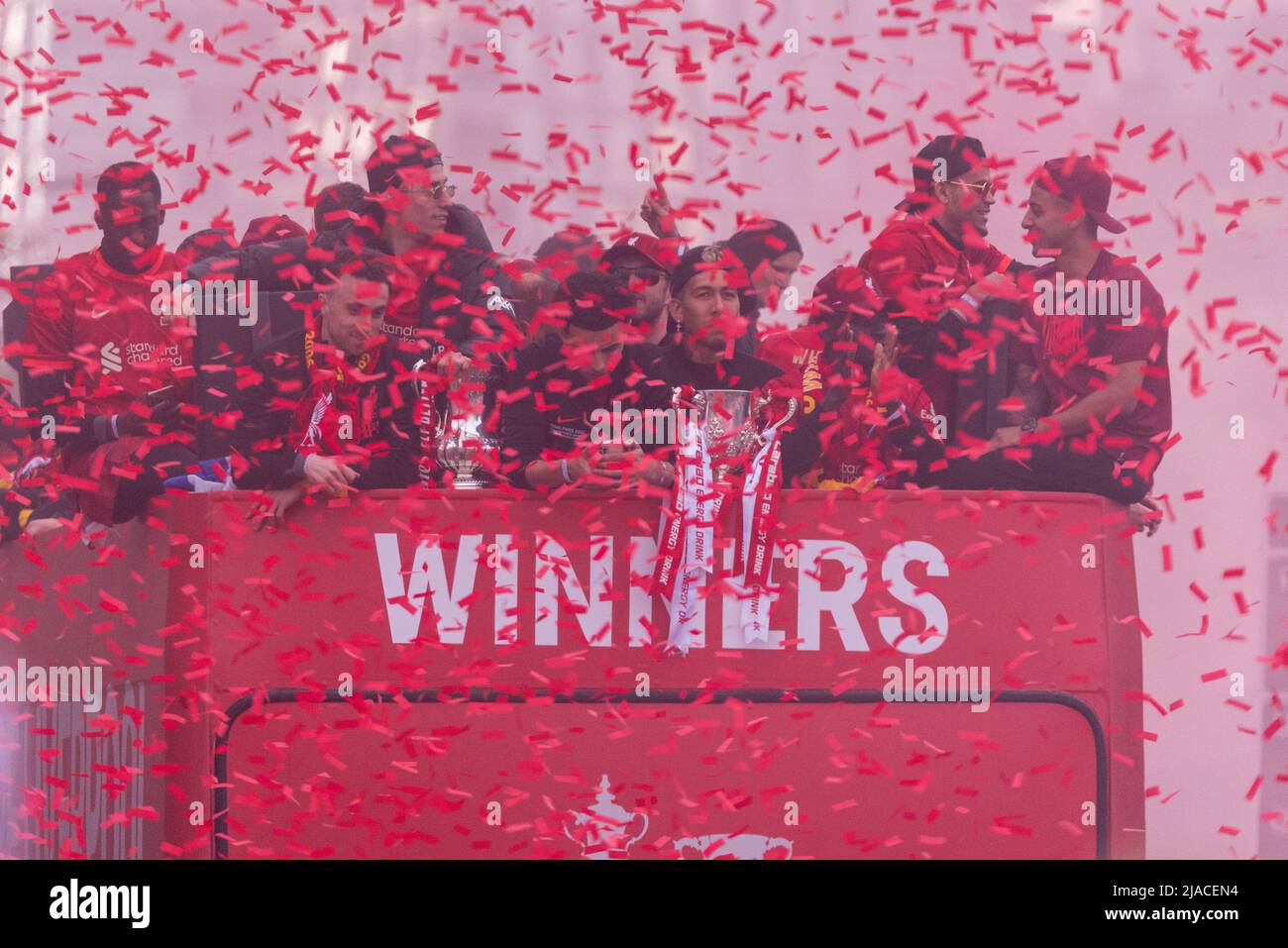 Baltic Triangle, Liverpool, UK. 29th May, 2022. The open-top bus parade to celebrate Liverpool FC’s trophy wins has taken place in the city with the manager and players of the team taking the applause from the fans lining the streets. The team showed off the League Cup and FA Cup trophies. Ticker tape and red smoke Stock Photo