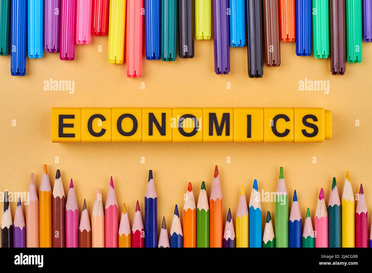 The word ECONOMICS written on plastic cubes in frame from colored school supplies. Flat lay. Stock Photo