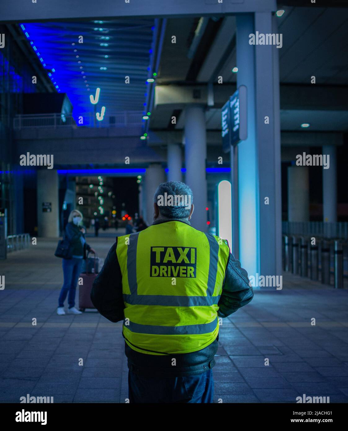Rear portrait of a taxi-driver standing in terminal 2, Manchester Airport, waiting for customers. Stock Photo