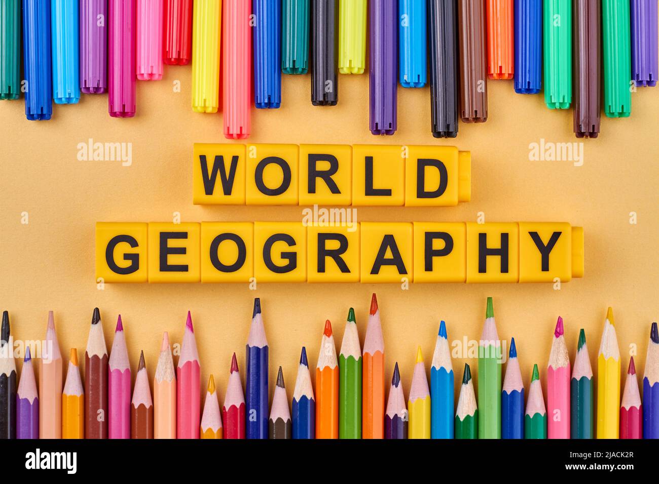 Flat lay composition with inscription world geography and colorful pencils. Education and travel concept. Stock Photo