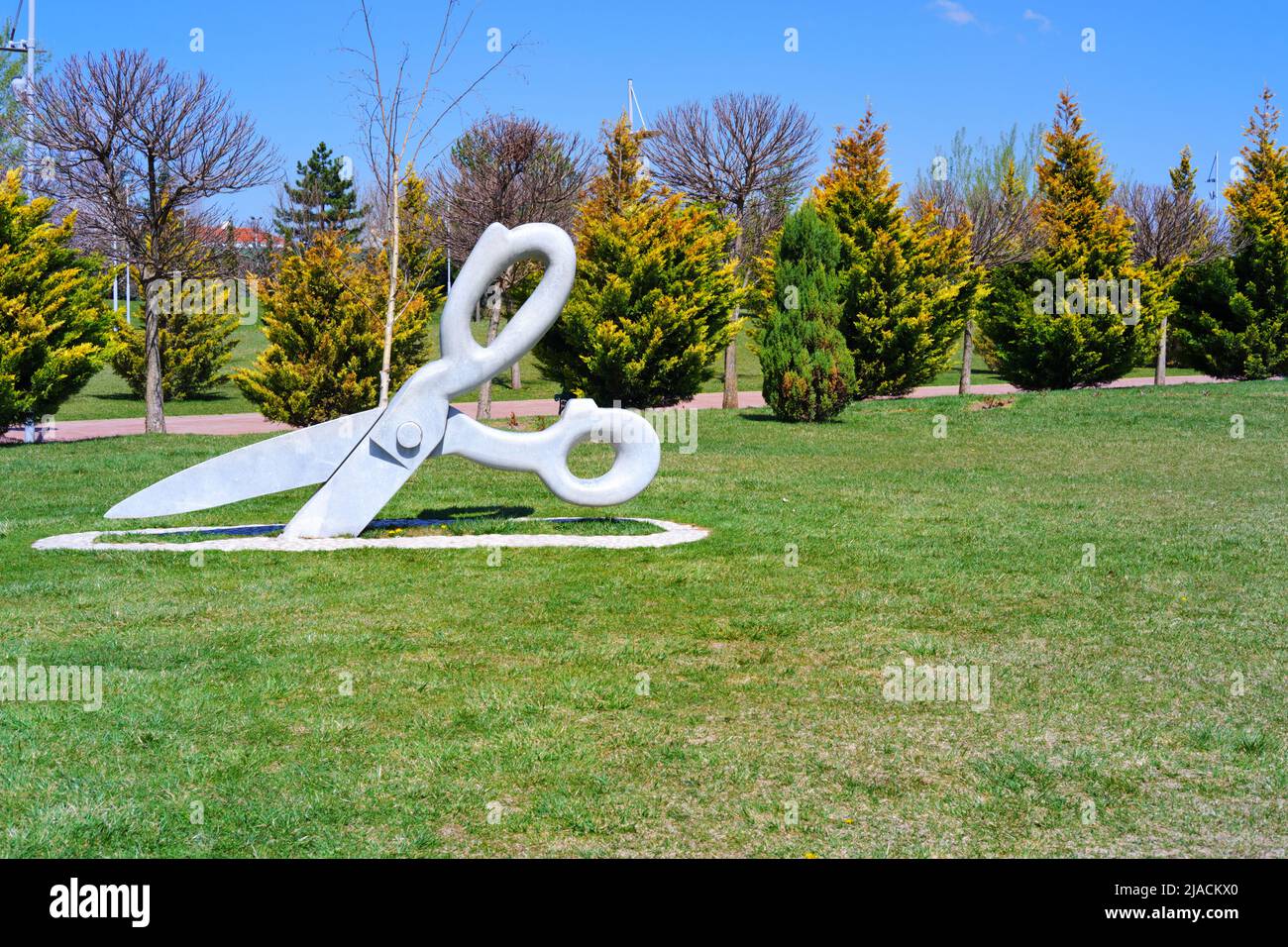 Statue of huge Scissor on the grass at park in a sunny summer day with