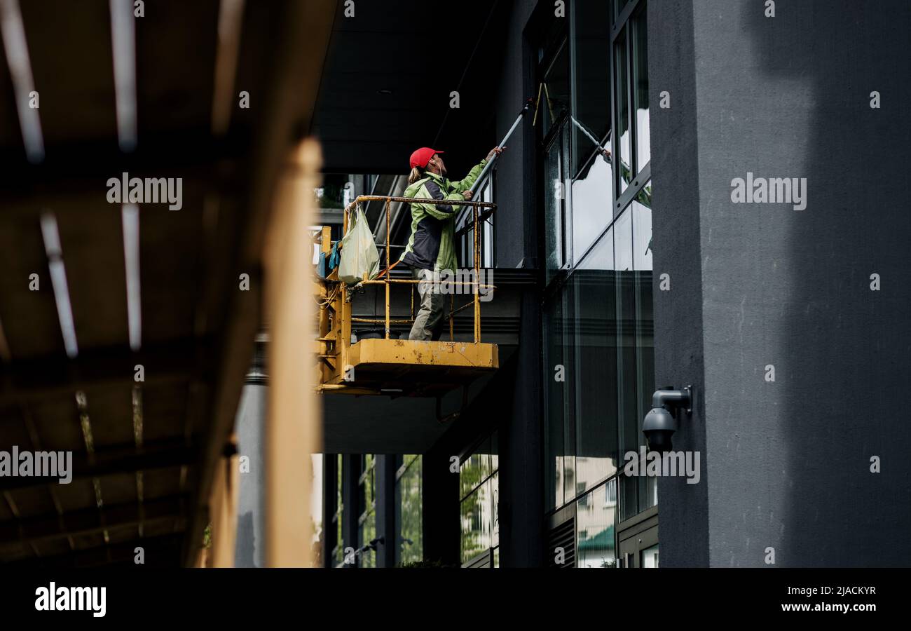 Female window cleaner cleaning glass windows on modern building high in