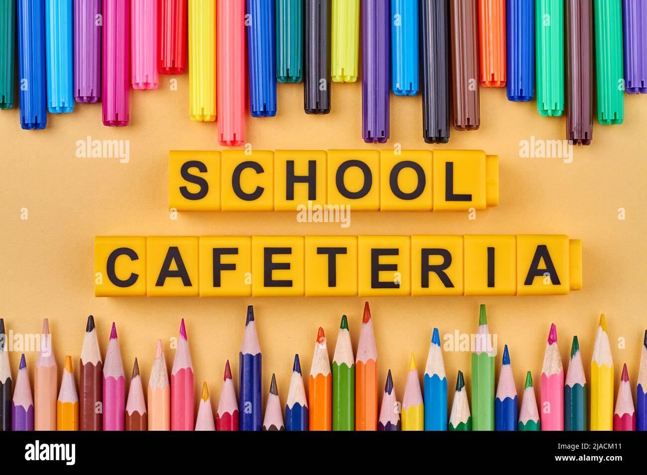 The inscription school cafeteria written on cubes. Colorful pencils and felt pens on table. Flat lay. Stock Photo