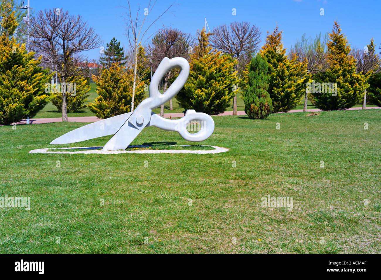 Statue of huge Scissor on the grass at park in a sunny summer day with
