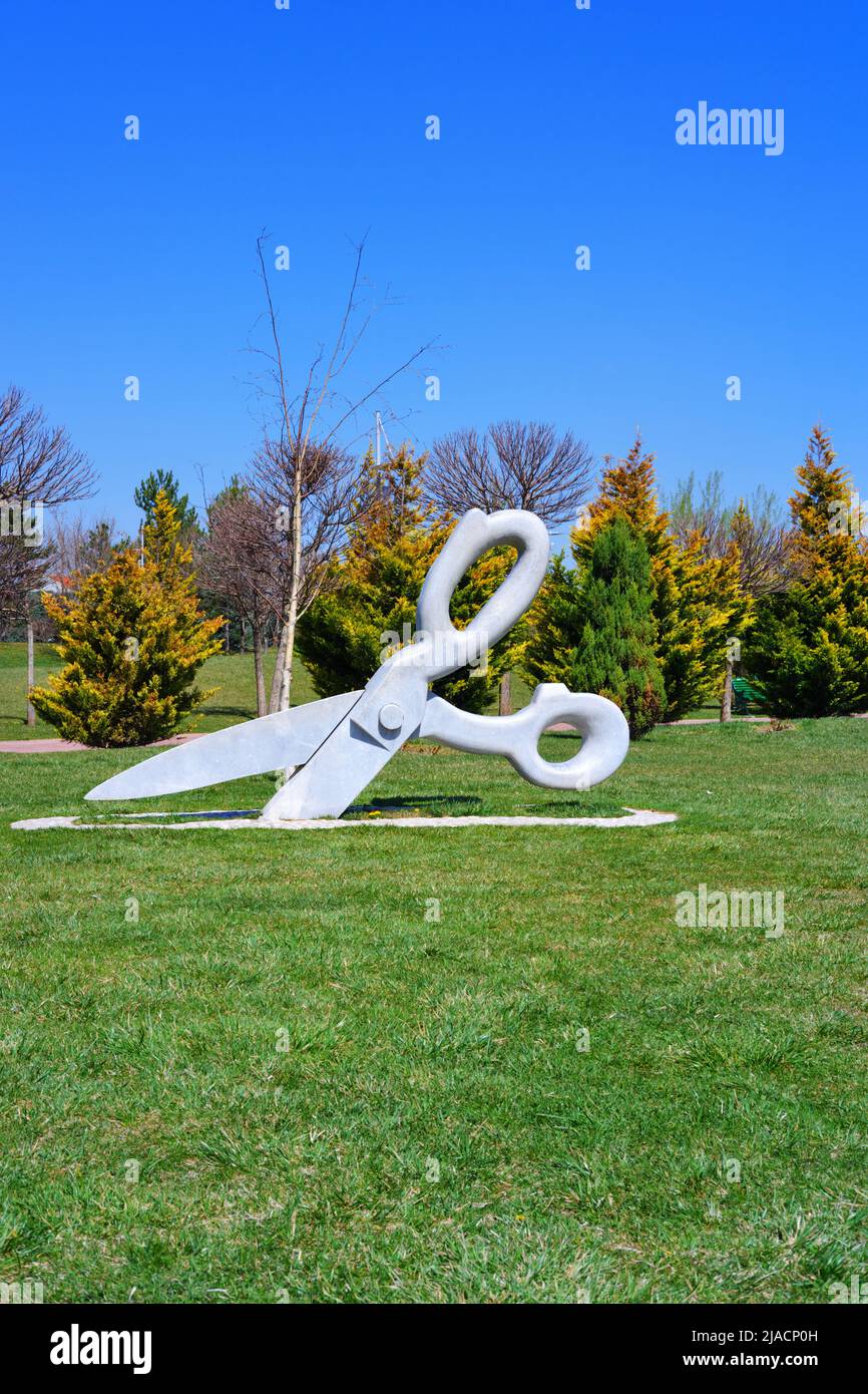 Statue of huge Scissor on the grass at park in a sunny summer day with