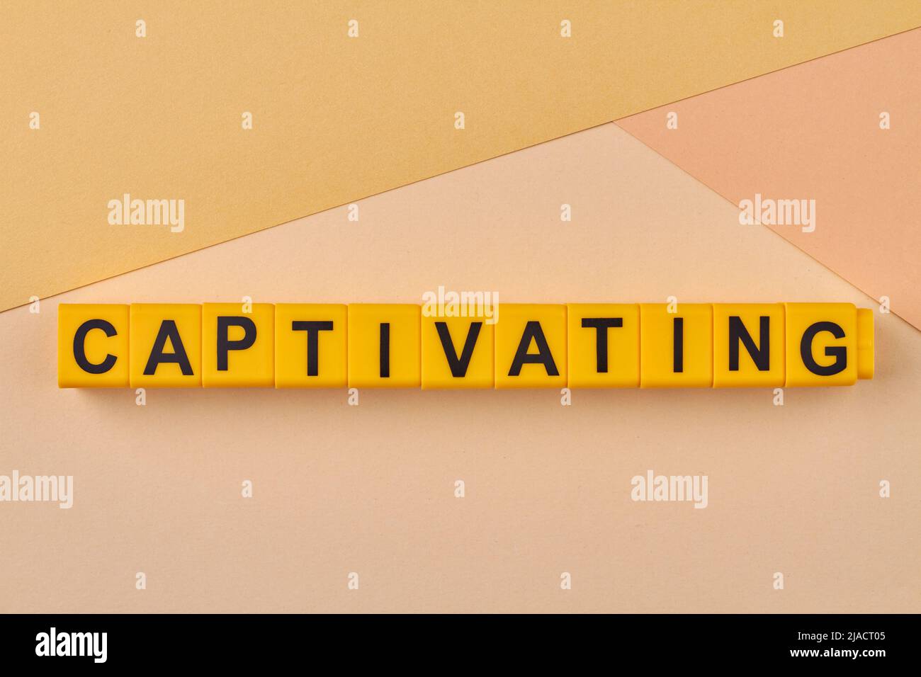 Captivating word written on alphabet blocks on light background close up. Capable of attracting and holding interest, charming. Stock Photo