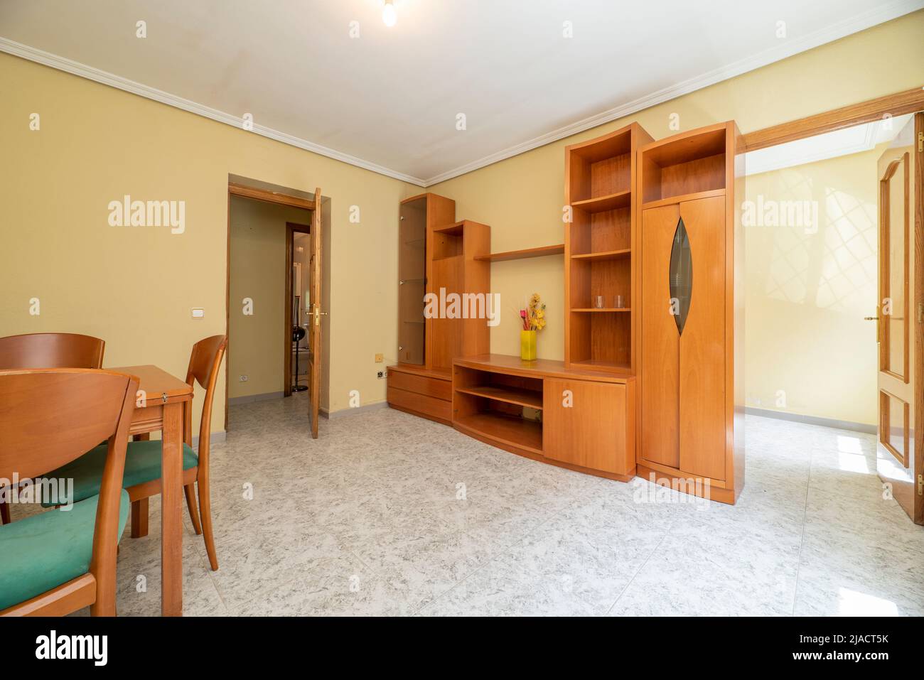 Living room with matching cherry colored bookcase with dining table and chairs Stock Photo