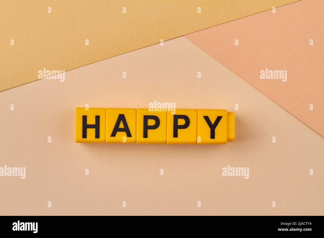 The word HAPPY written on yellow cubes close up. Feeling or showing pleasure or contentment. Fortunate and convenient. Stock Photo