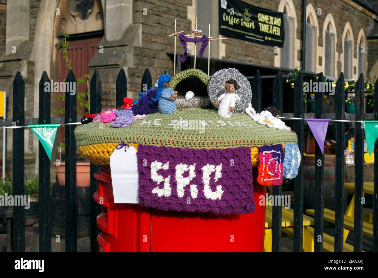 Easter scene as a knitted crafted woollen postbox topper, in front of a church. Stock Photo