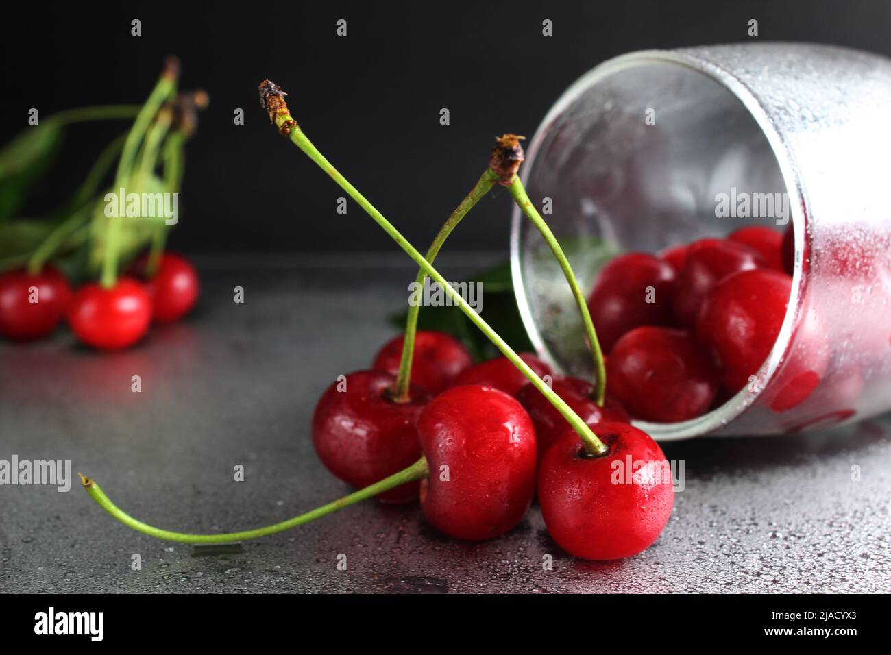 cherry red ripe berry fell out of the glass on a black background with