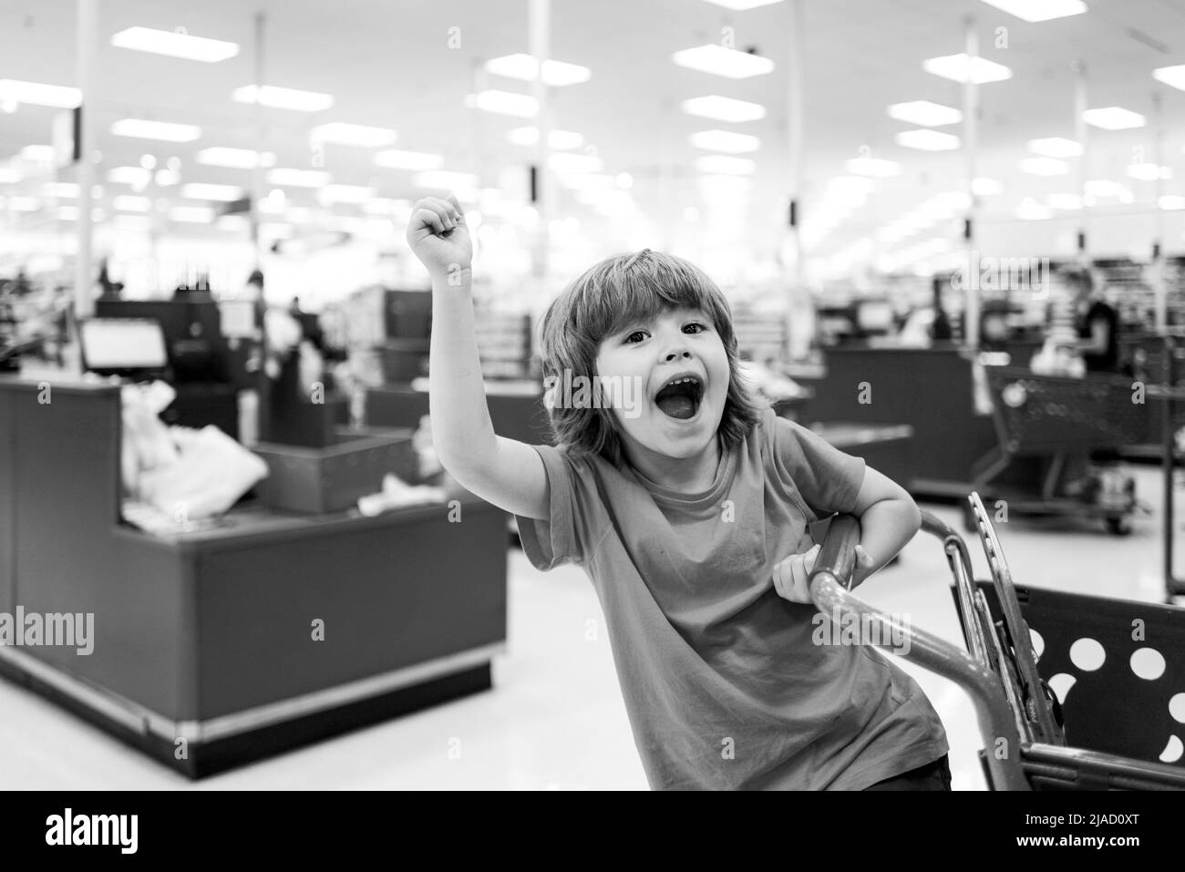 Kid in supermarket shop. Toddler boy with shopping bag in store. Stock Photo