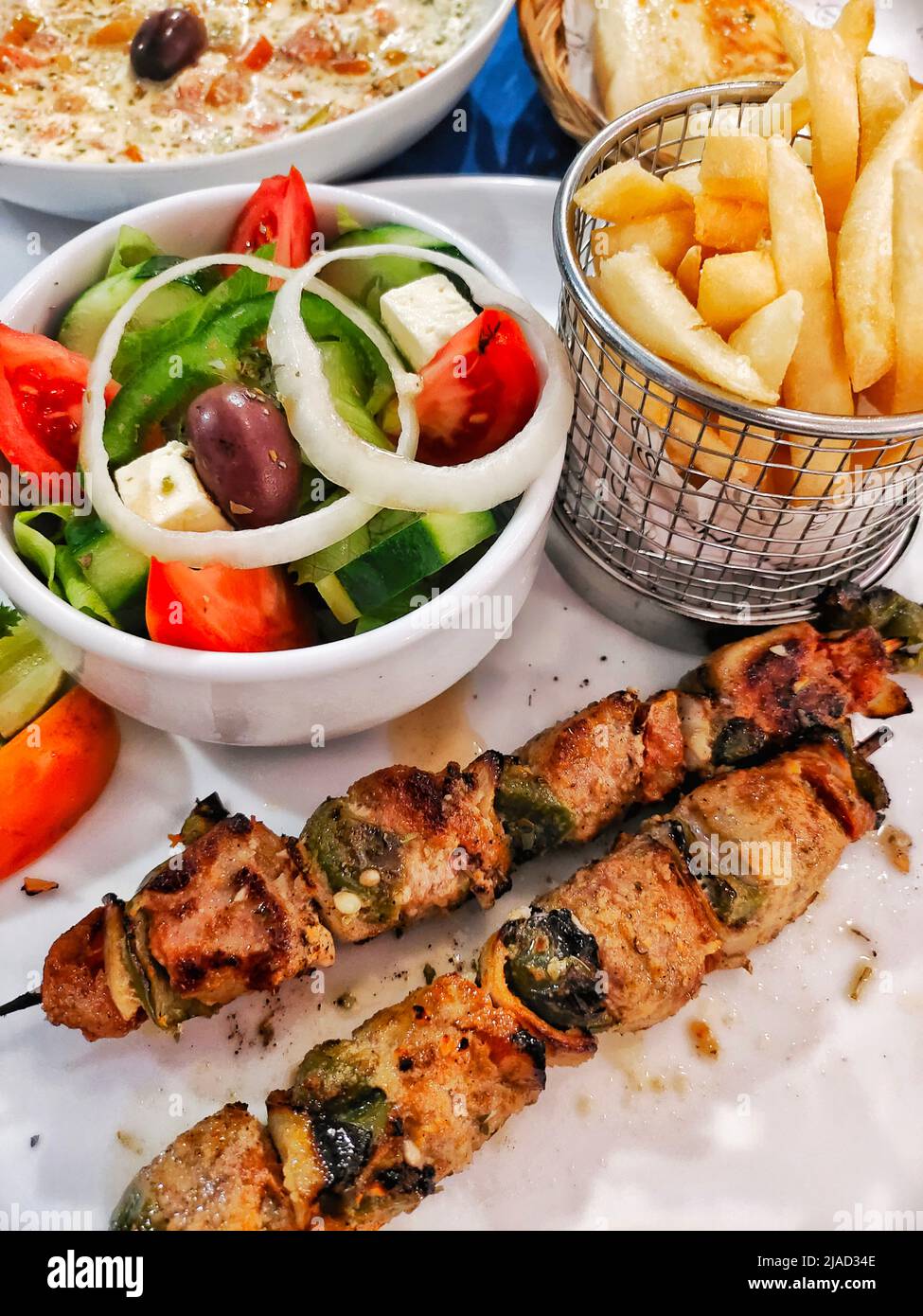 Souvlaki with a greek salad, chips, bread and dip Stock Photo
