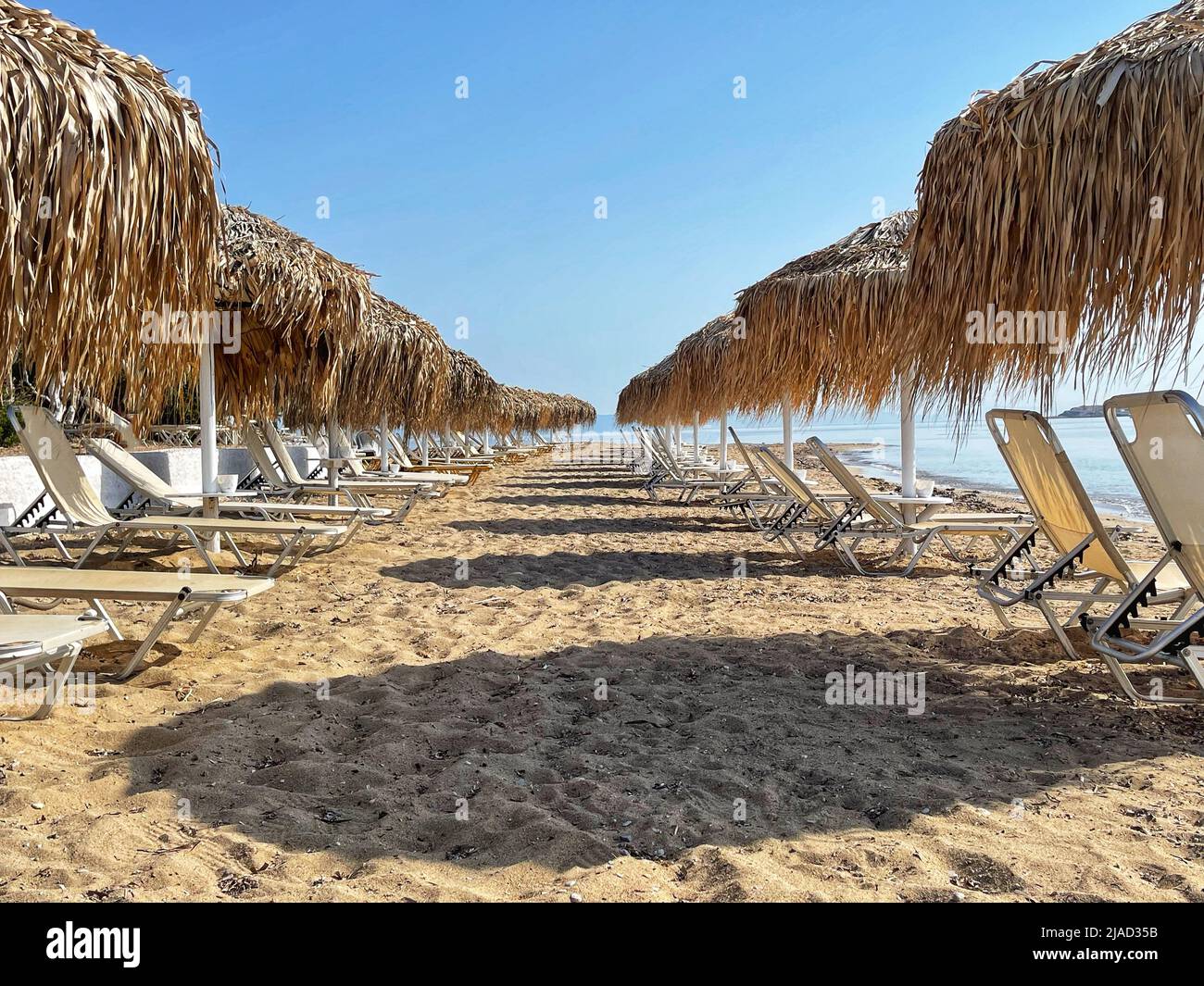 Rows of sun loungers on Aquarius Beach, Skala, Agistri, Attica, Greece Stock Photo