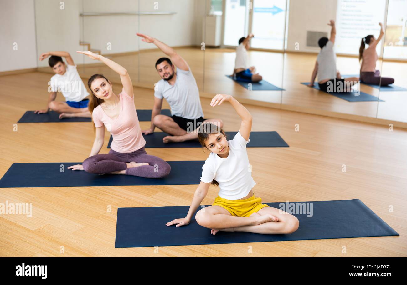 Preteen girl stretching in lotus position during family training Stock ...