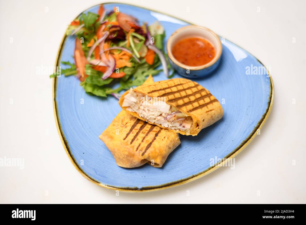 Toasted chicken, cheese and red onion tortilla wrap with salad and chili dip sauce Stock Photo