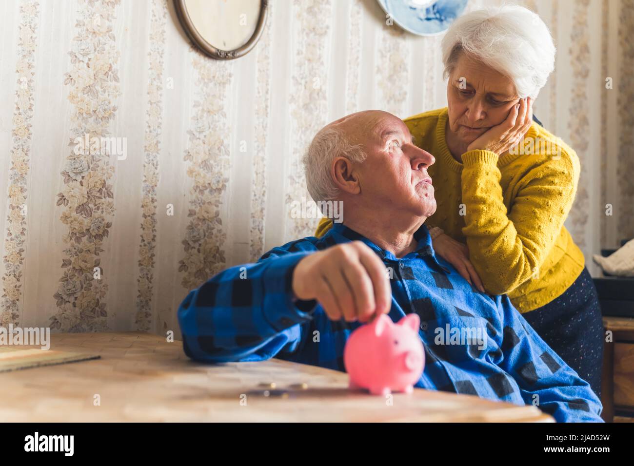 worried elder couple with a piggybank on the table medium shot living room financial problems concept. High quality photo Stock Photo