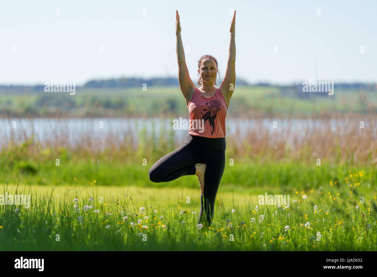 Woman doing tree pose by Wallersee, Salzburg, Austria Stock Photo