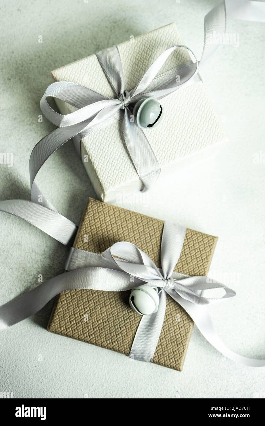 Two gift boxes on a table wrapped with ribbons and bells Stock Photo