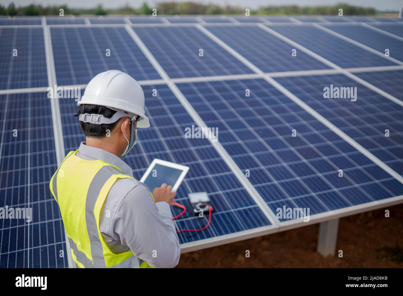Tablet Using Solar Panel Engineer with a digital tablet standing next to solar panels at a solar ...