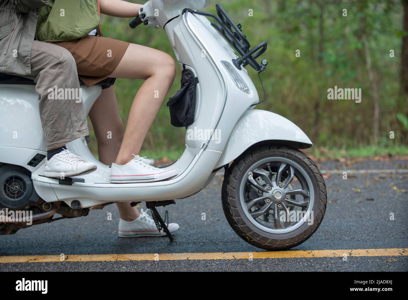 Close-up side view of a couple sitting on a scooter Stock Photo