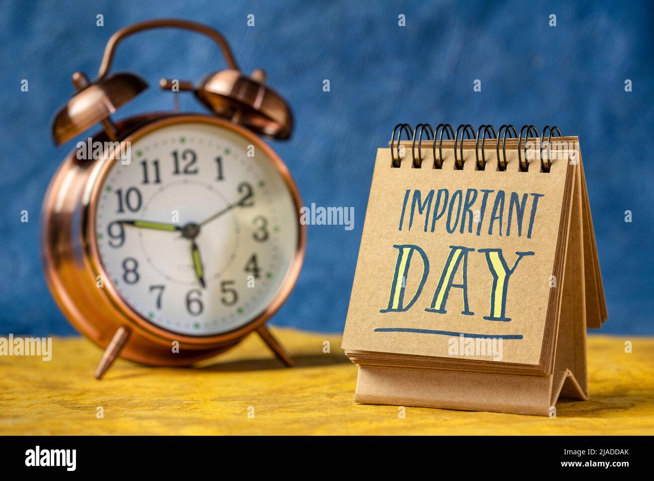 important day reminder note in a desktop calendar with an alarm clock Stock Photo