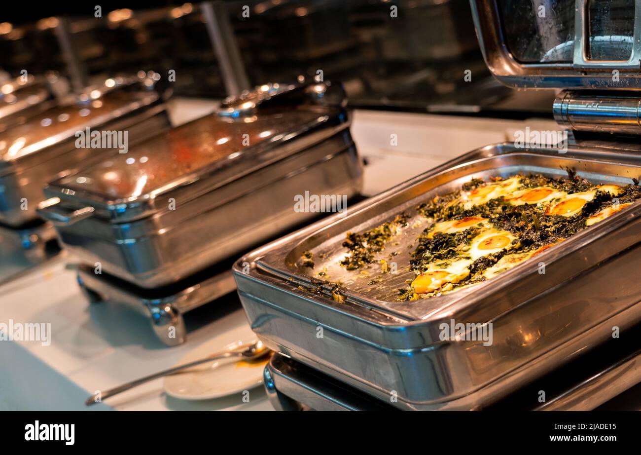 Breakfast buffet food in heating trays in hotel restaurant with eggs