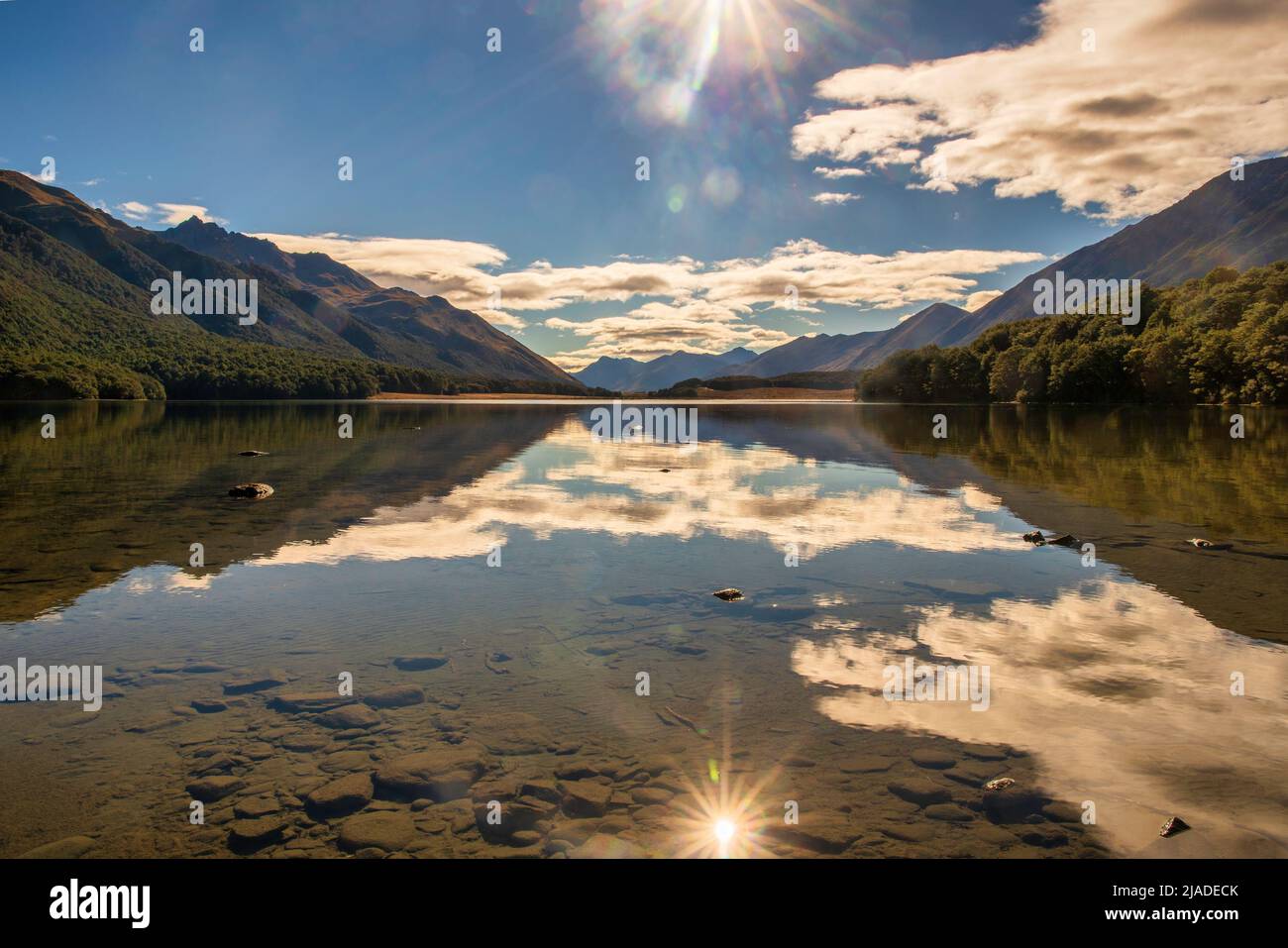 Sky cloud and sun burst reflection on South Mavora Lake in remote  Fiordland national Park Stock Photo