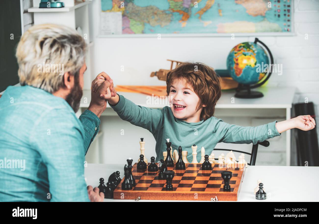 Young kid boy playing chess with father and having fun. Education and learning people concept - pupil and Teacher. Stock Photo