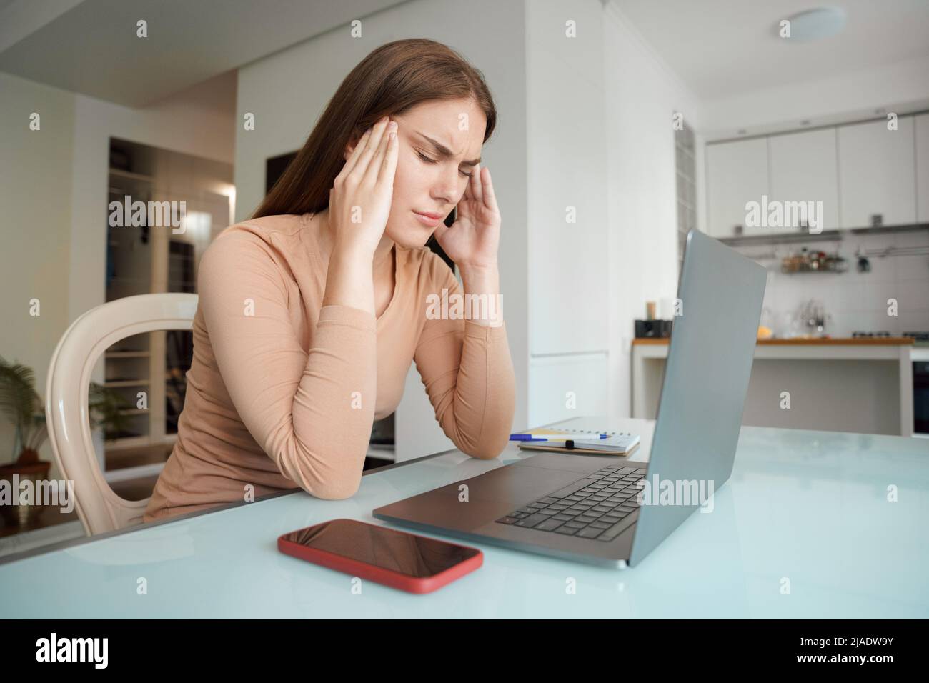 Stressed young woman suffering from headache after computer work Stock Photo