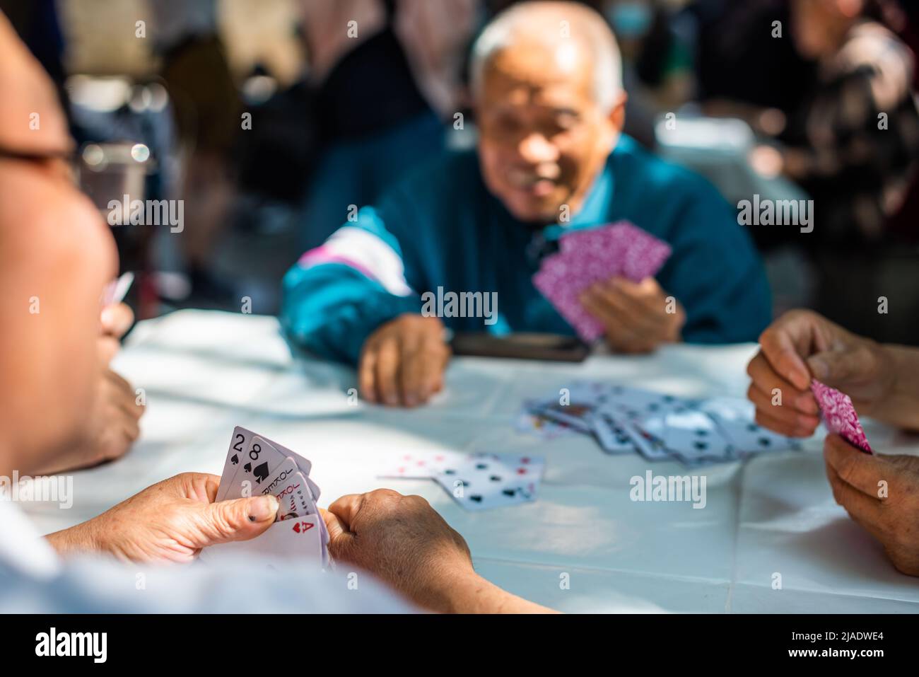 Senior Chinese people playing cards outdoors Stock Photo